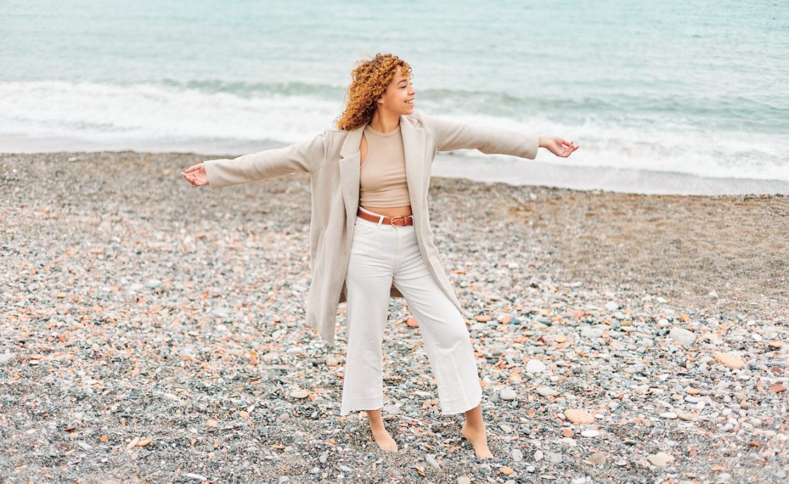Young afro american woman with curly hair is happy on the coast.